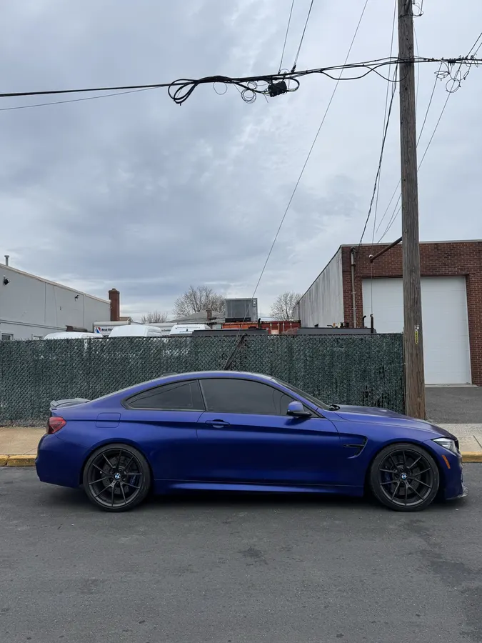 Deep blue BMW M3 with freshly installed ceramic window tint in the shop bay