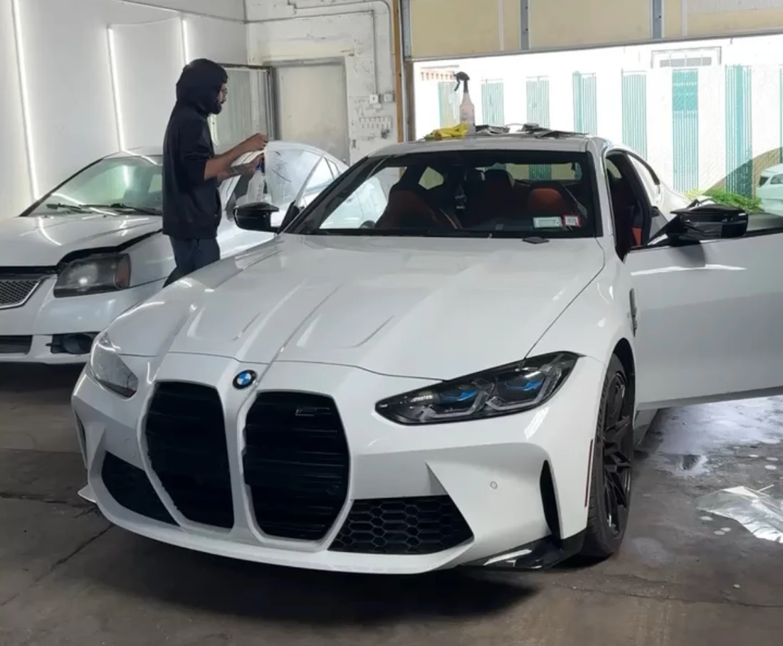 White BMW M4 in the shop while automotive window tint is being installed