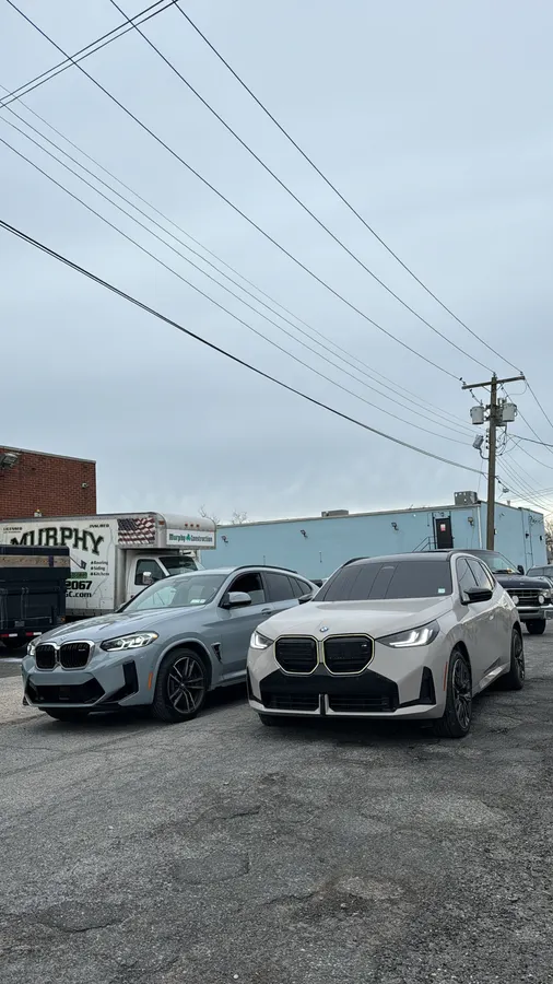 A row of high-end vehicles including BMW M and Porsche models parked outside the Visionary Auto Spa shop