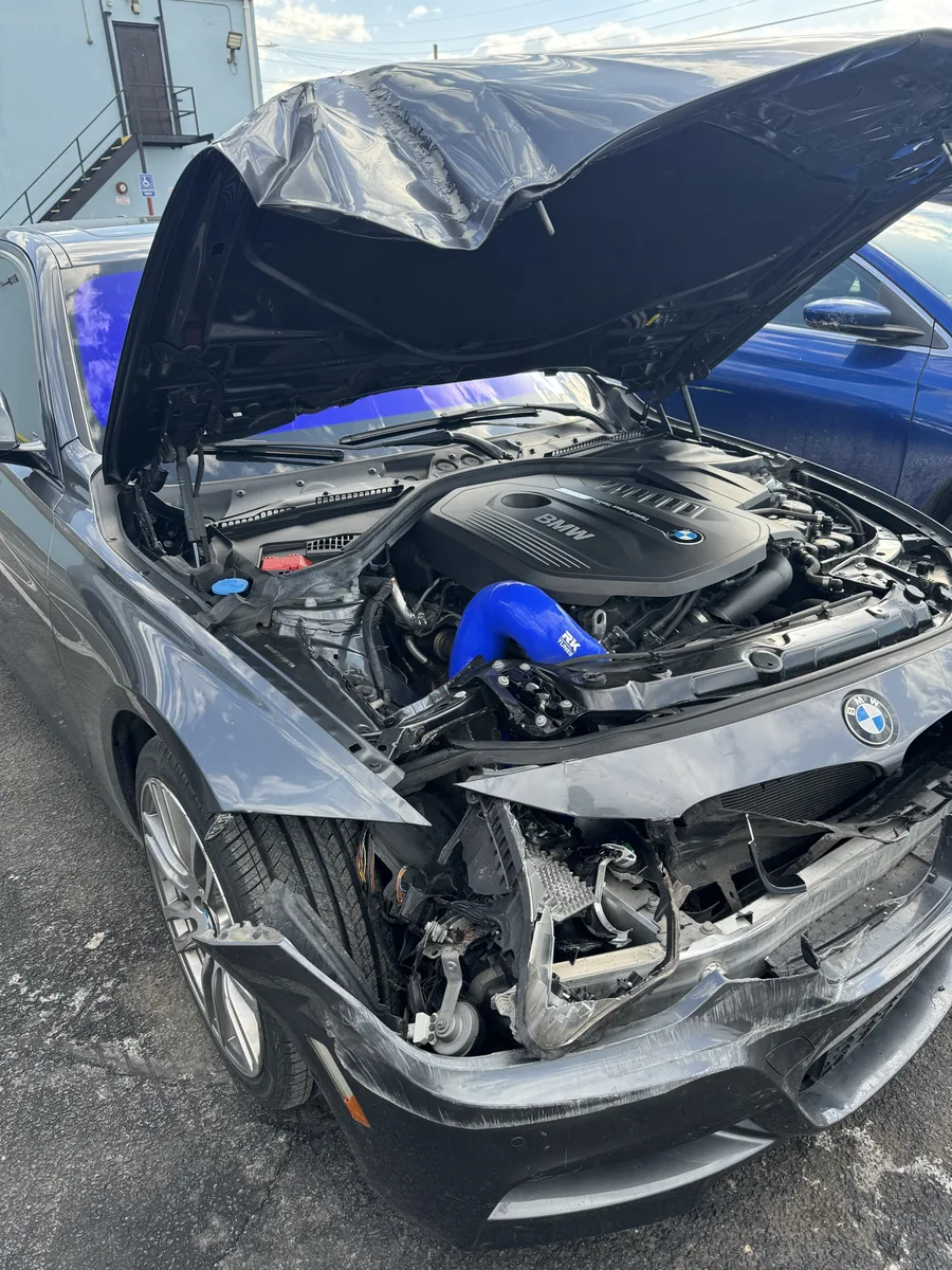 White Mercedes SUV with front-end collision damage being documented for an insurance estimate