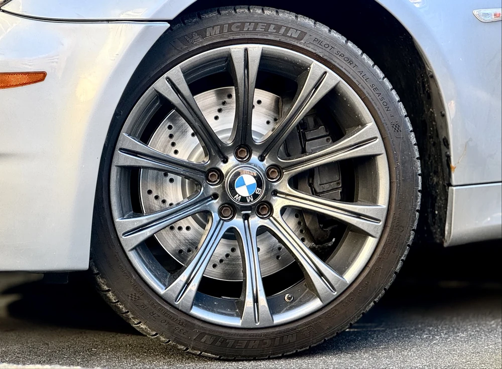 Close-up of a BMW wheel, tire, and drilled brake rotor during performance service